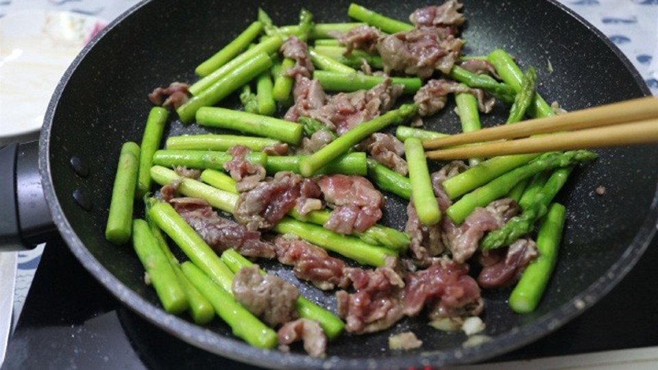 Đang xào măng tây trong chảo