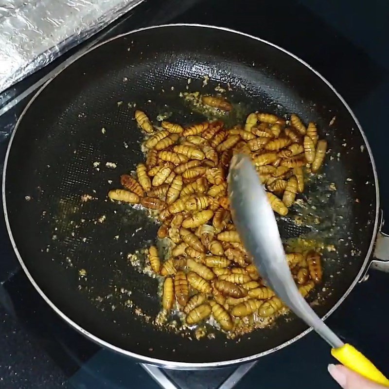 Đảo đều nhộng ong trong chảo để thấm đều hương vị bơ tỏi