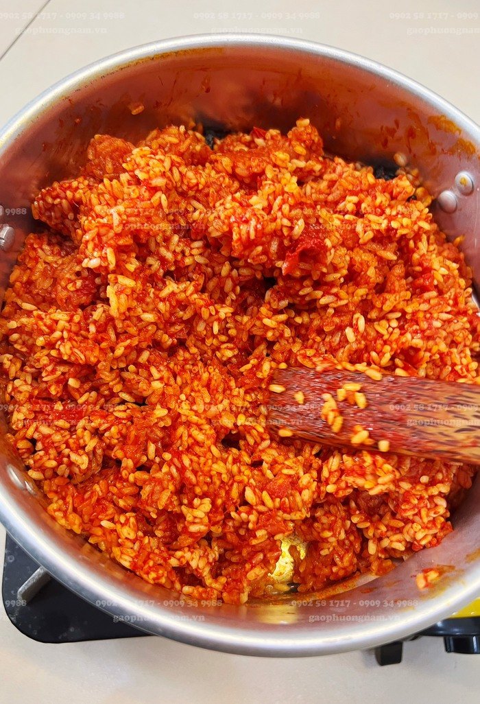 Đảo đều xôi gấc khi hấp để xôi chín tới, mẹo quan trọng trong cách nấu xôi gấc bằng xửng hấp