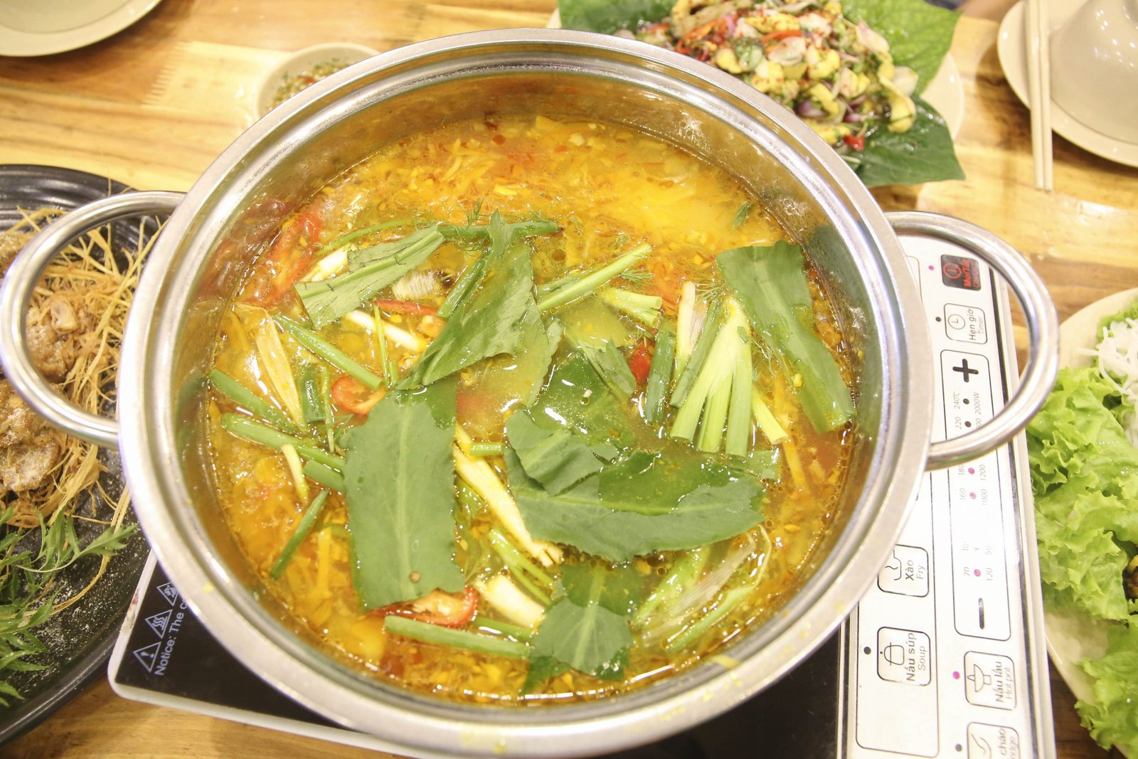 Đầu bếp đang xào nền lẩu hải sản với dứa, cà chua và các loại gia vị