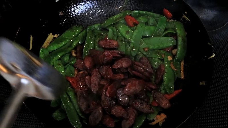 Đĩa đậu Hà Lan xào lạp xưởng đã hoàn thành, bày biện đẹp mắt trên bàn ăn.