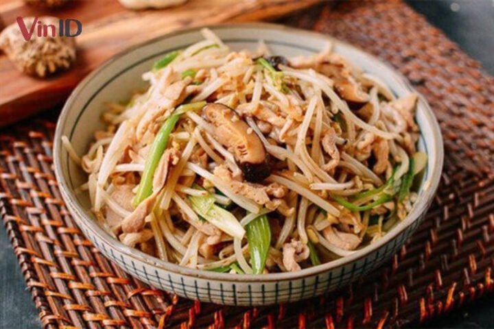 Đĩa gà xào giá đỗ với hành lá và nấm hương thơm ngon, sẵn sàng cho bữa ăn gia đình.