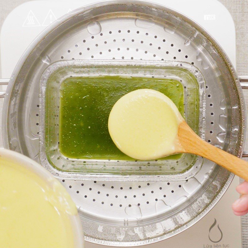 Đổ một vá bột bánh da lợn màu vàng vào khuôn trên xửng hấp, tạo lớp bánh tiếp theo sau lớp xanh