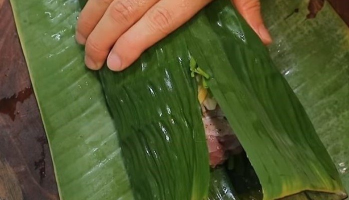 Gói kín miếng thịt heo muối bằng lá chuối và giấy bạc để chuẩn bị ủ.