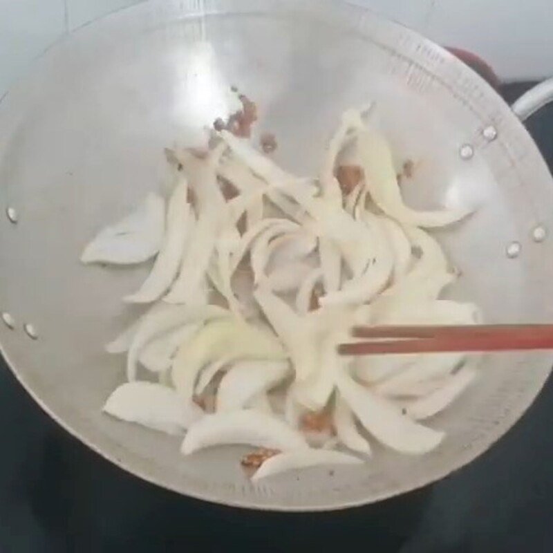 Hành tây và ớt chuông đang được xào trên chảo nóng, tỏa hương thơm lừng