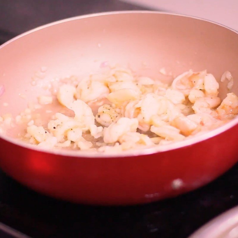 Hành và tỏi băm đang được phi thơm trên chảo nóng, tạo lớp hương nền cho món xào