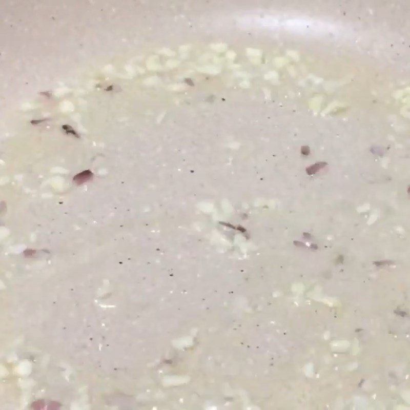 Hành và tỏi băm đang được phi thơm trong chảo dầu nóng, là bước đầu cho món xào