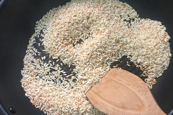 Hạt gạo được rang vàng nhẹ, chuẩn bị cho món cháo thịt bằm nhừ thơm