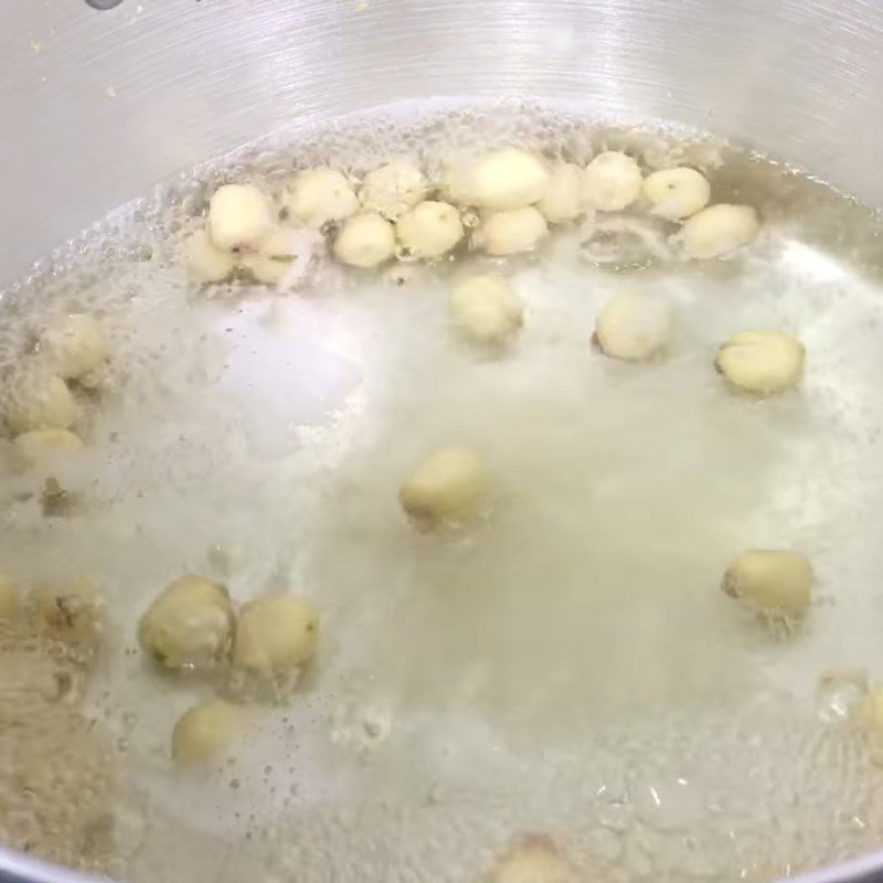 Hạt sen đang sôi cùng hỗn hợp bột bắp, tạo nền cho món chè cốm lá dứa