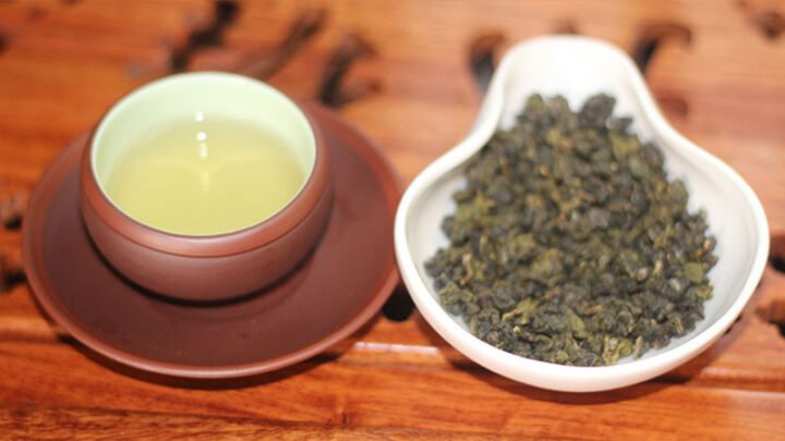 Hình ảnh lá trà ô long tươi và khô, minh họa thành phần caffeine và polyphenols giúp thúc đẩy trao đổi chất và giảm chất béo trong trà ô long