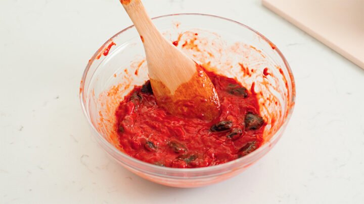 Hình ảnh phần thịt gấc đỏ tươi được tách ra khỏi hạt để chuẩn bị nấu xôi.