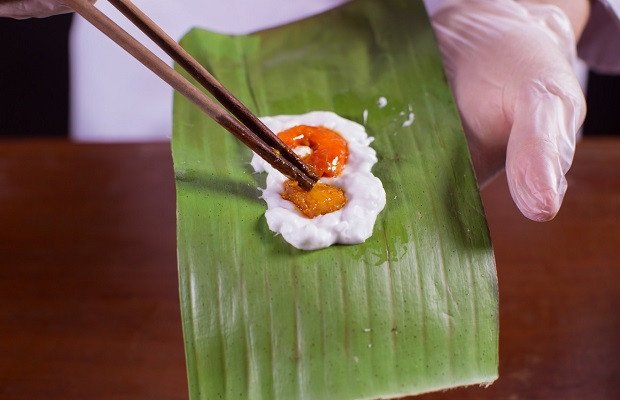 Hình ảnh quá trình đặt nhân tôm thịt đậm đà vào lớp bột chuẩn bị làm bánh bột lọc gói lá chuối.