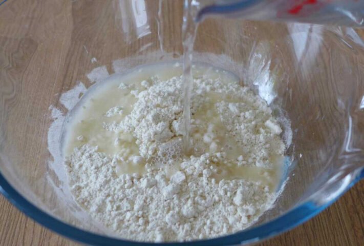 Hình ảnh quá trình thêm nước sôi vào bột mì để làm vỏ bánh hành chiên Trung Quốc, chuẩn bị cho bước nhào bột.