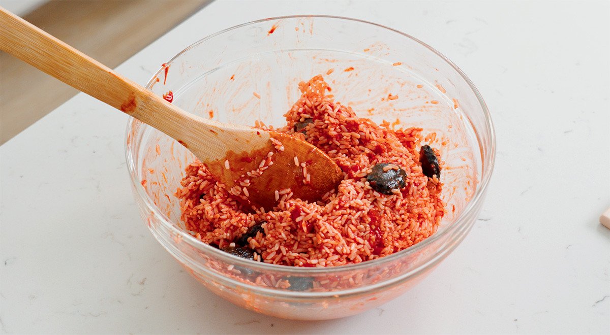 Hỗn hợp gạo nếp và thịt gấc được trộn đều, tạo màu cam rực rỡ cho xôi.