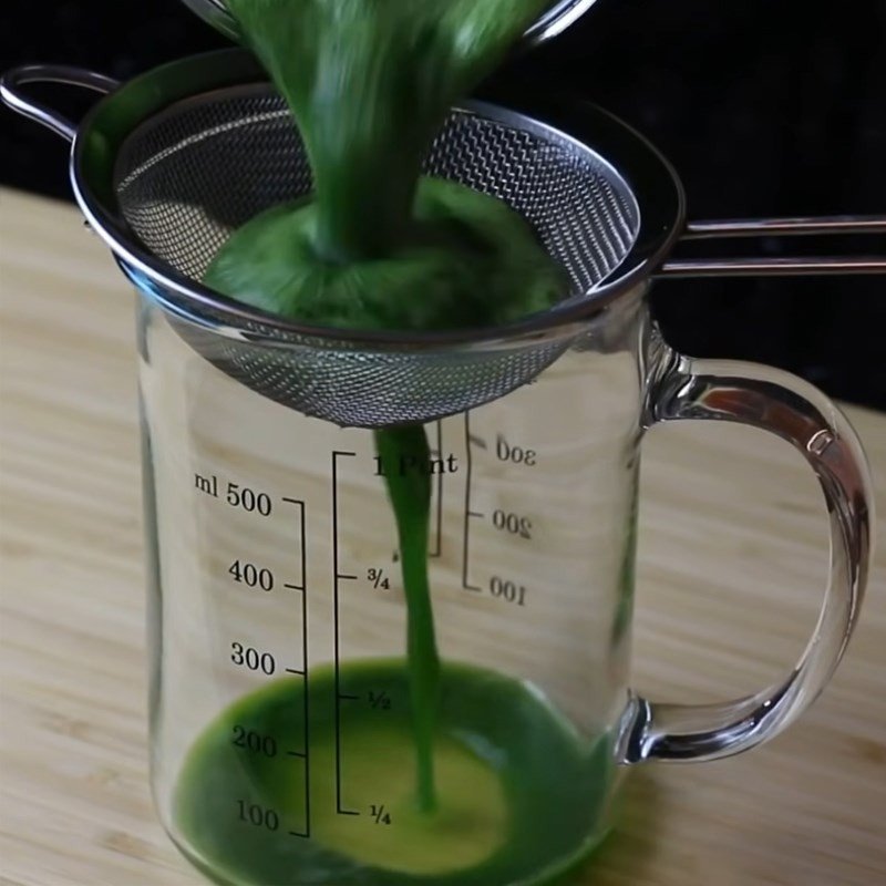 Lọc nước cốt lá dứa qua rây để có được màu xanh tự nhiên và hương thơm đặc trưng cho bánh đúc gân