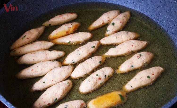 Miếng bánh khoai mì chiên cay đang được chiên vàng đều trên chảo nóng