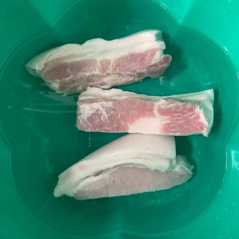 Miếng thịt ba chỉ được rửa sạch dưới vòi nước, chuẩn bị cho quá trình sơ chế để loại bỏ mùi hôi và tạp chất, đảm bảo món thịt rim mặn ngọt có hương vị tốt nhất