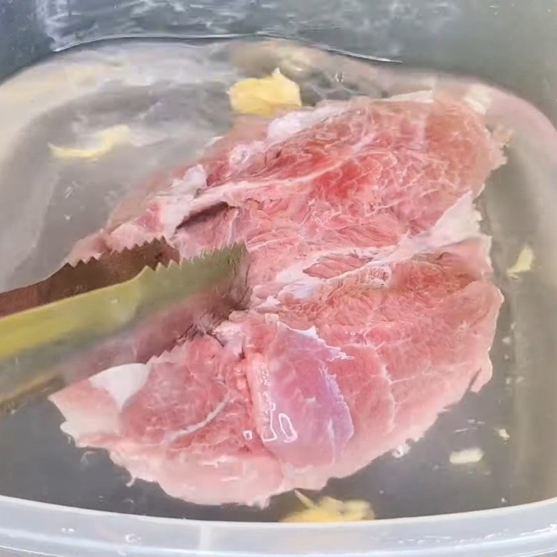 Miếng thịt lợn luộc đã chín và chuẩn bị được thái để làm nộm