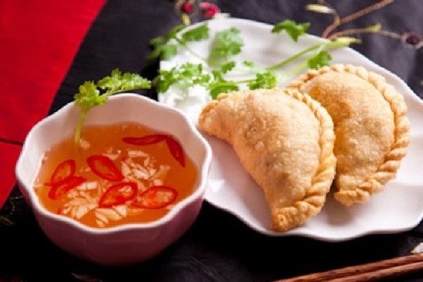 Món bánh gối chiên vàng giòn kèm nước chấm và rau sống