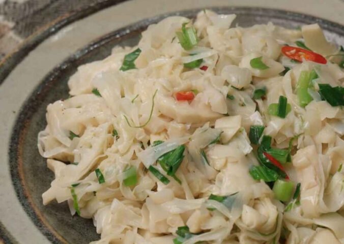 Món măng đắng xào tỏi đang được chế biến trên chảo nóng