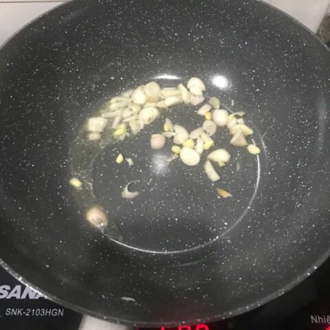 Món thịt chua ngọt đang được xào trên chảo nóng, hòa quyện hương vị.