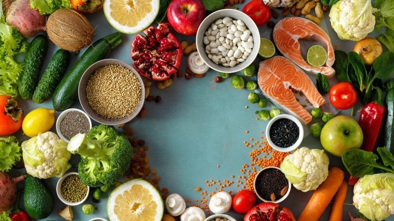 Một bữa ăn lành mạnh với nhiều rau xanh và hoa quả bên cạnh một miếng bánh bông lan trứng muối, cân bằng giá trị dinh dưỡng bánh bông lan