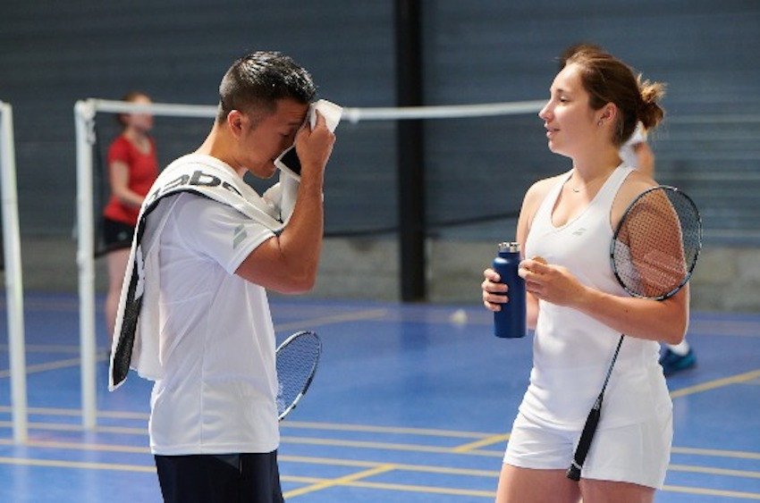 Một chai nước và khăn bên cạnh sân cầu lông, tượng trưng cho việc bổ sung nước khi vận động