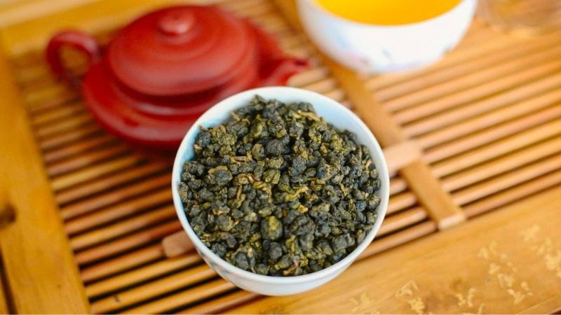 Một ly trà ô long truyền thống với lá trà xanh, tượng trưng cho khả năng hỗ trợ giảm cân và đốt cháy mỡ thừa của trà ô long