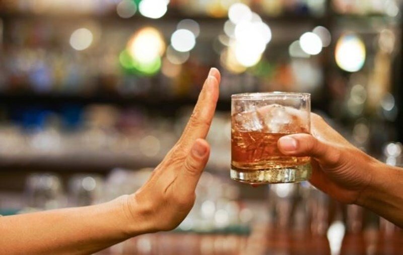 Một người đàn ông đang đổ rượu từ bình ra chén, minh họa việc kiểm soát liều lượng khi uống rượu