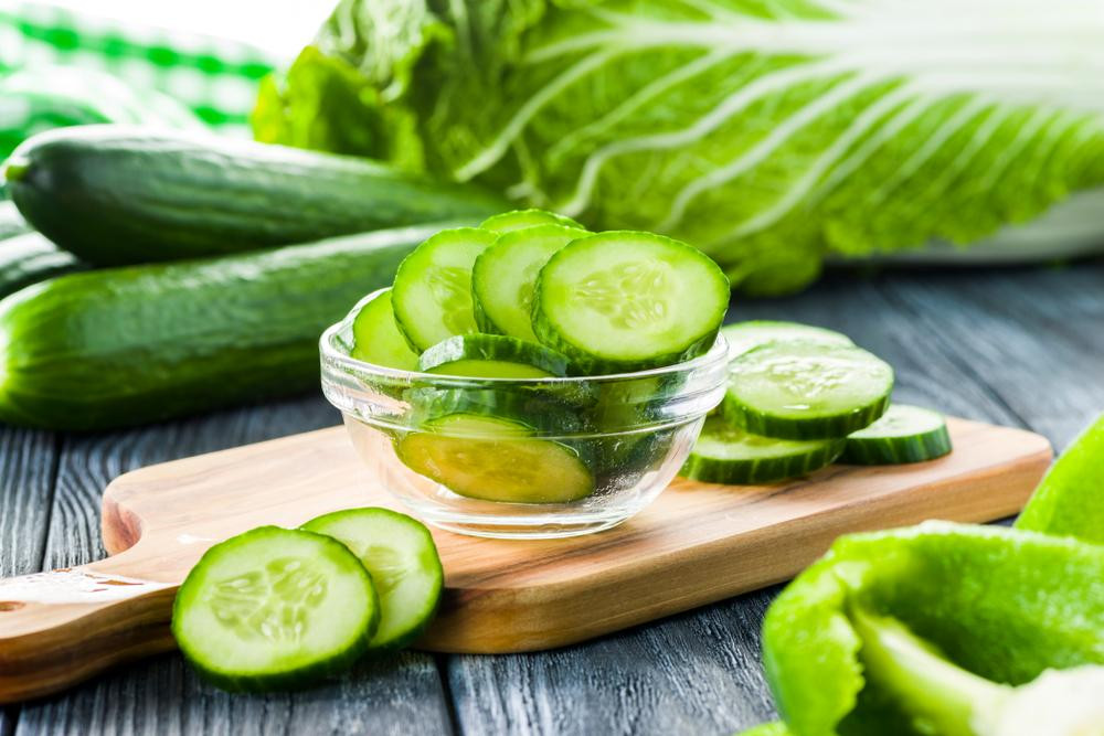 Một người đang cầm quả dưa chuột, nhấn mạnh sự tiện lợi của việc sử dụng dưa chuột trong các bữa ăn hàng ngày để kiểm soát calo.