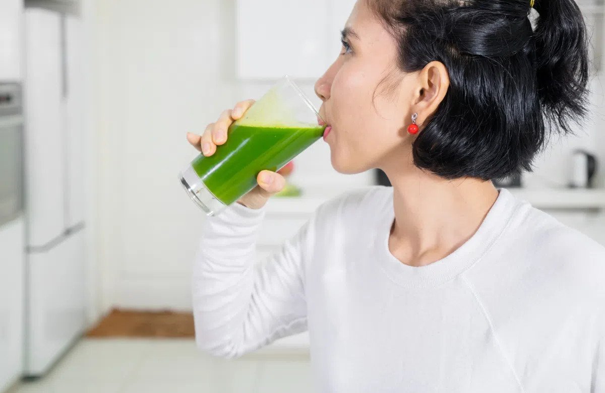 Một người phụ nữ trẻ đang uống nước rau diếp cá, minh họa việc sử dụng đúng liều lượng.