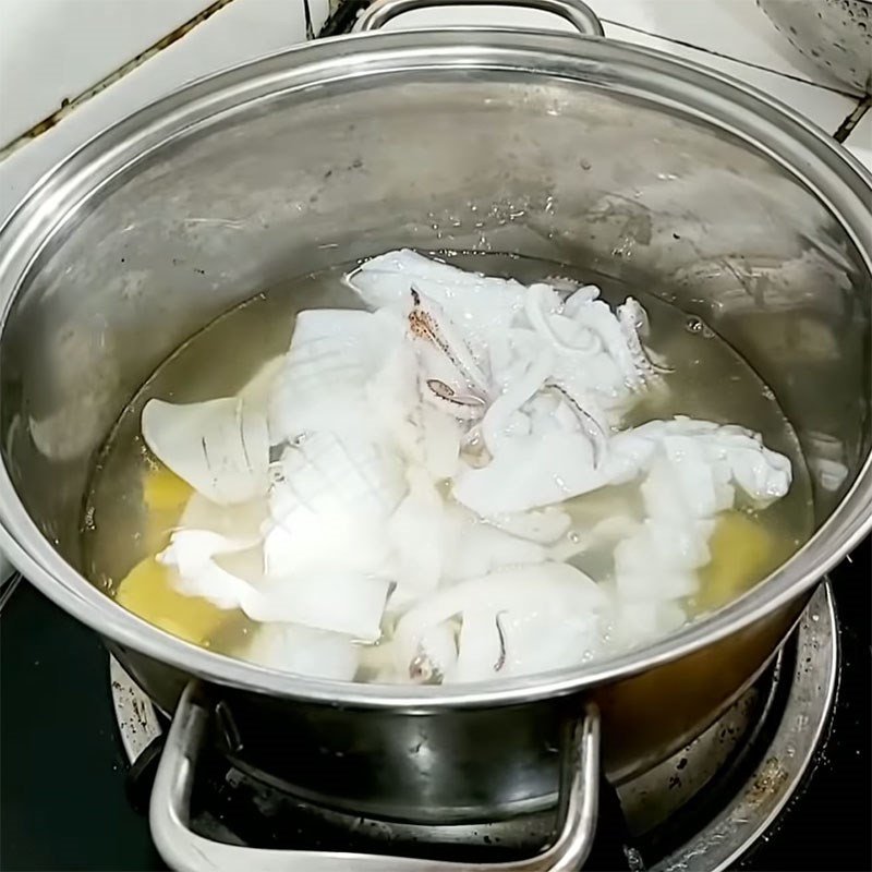 Mực đang được chần nhanh trong nồi nước sôi có gừng và rượu để khử mùi tanh và giữ độ giòn