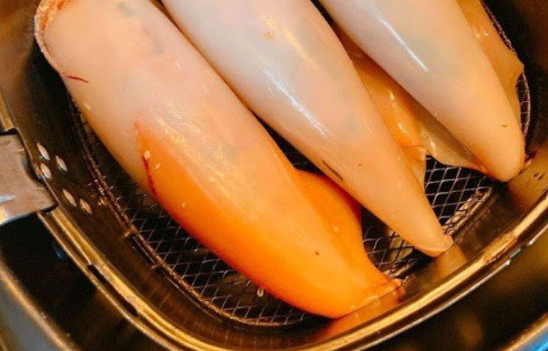 Mực nhồi thịt đang được nướng vàng đều trong nồi chiên không dầu, tạo lớp vỏ giòn rụm