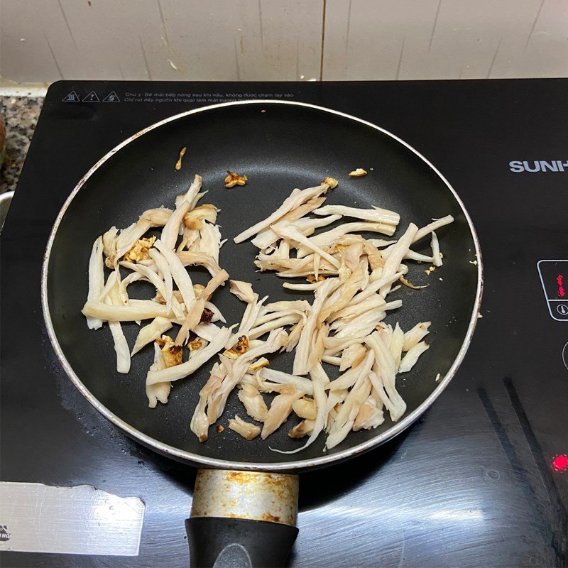 Nấm đùi gà đang được xào trên chảo với tỏi thơm để tăng hương vị cho cháo nấm chay
