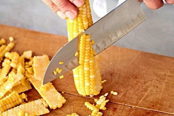 Người đang tách hạt ngô khỏi cùi bằng tay để chuẩn bị làm bánh ngô chiên