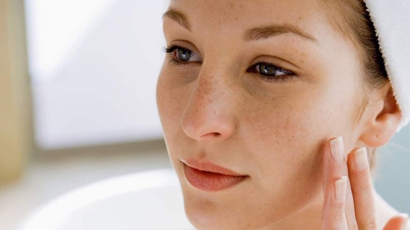 Người phụ nữ chạm vào làn da của mình, biểu thị lo ngại về tình trạng da sạm, nổi mụn do đường