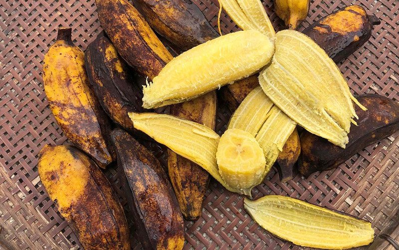 Người phụ nữ đang cầm quả chuối luộc, minh họa giá trị dinh dưỡng của chuối luộc