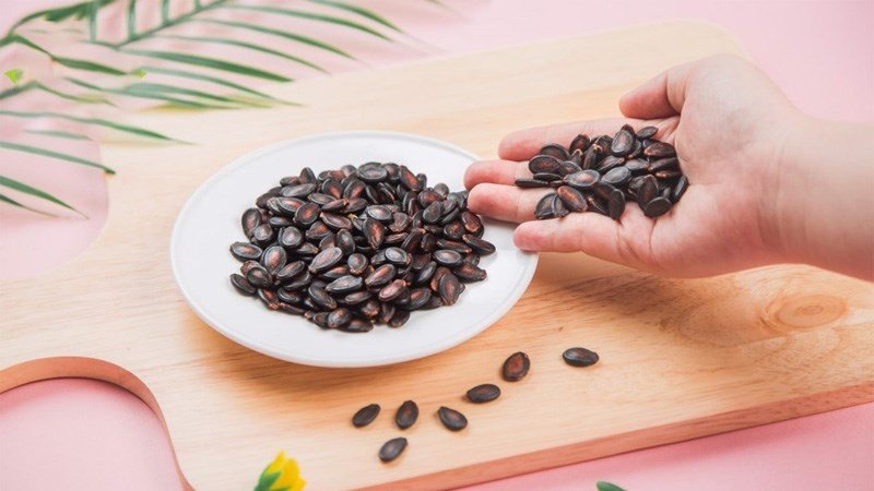 Người phụ nữ đang cân nhắc lượng hạt dưa ăn vào để kiểm soát cân nặng và tránh nạp quá nhiều calo