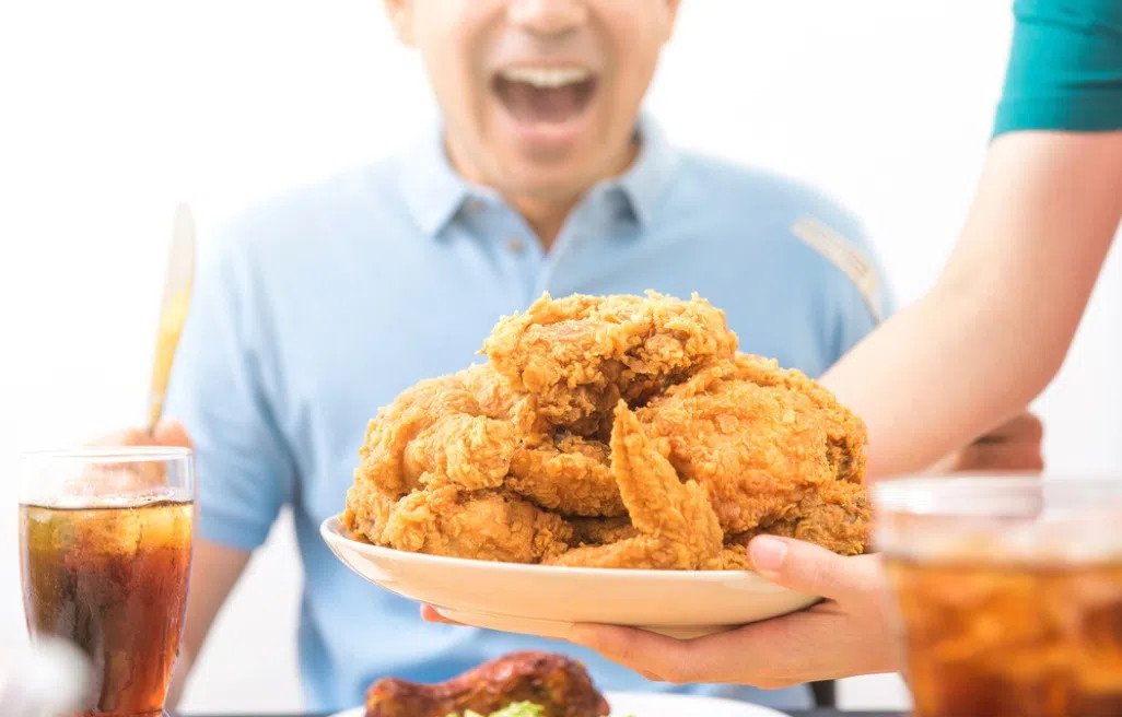 Người phụ nữ đang thưởng thức một miếng gà rán nhỏ kèm theo salad tươi xanh, minh họa cách ăn gà rán hợp lý và cân đối dinh dưỡng