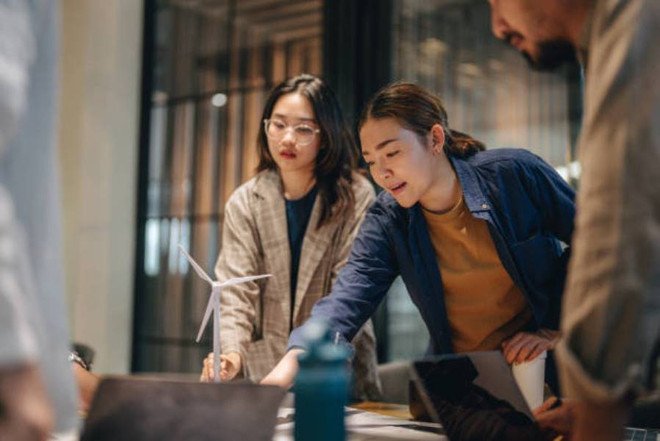 Người phụ nữ đứng làm việc tại bàn, nhìn vào màn hình máy tính