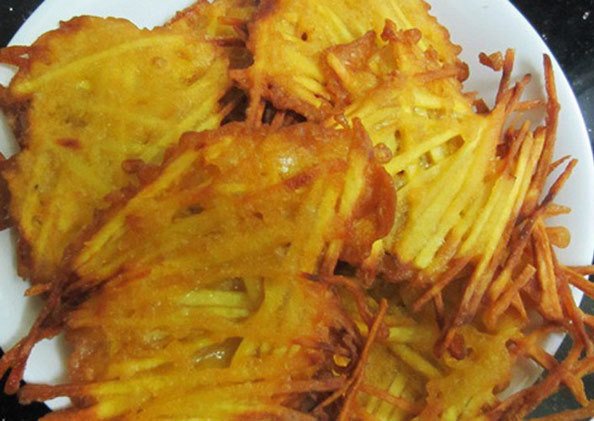 Những chiếc bánh khoai lang chiên vàng giòn đang được chiên trong chảo dầu nóng