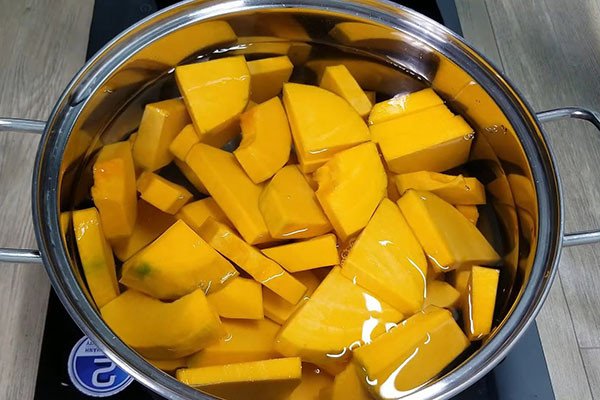 Nồi bí đỏ đang được luộc chín mềm để thực hiện cách nấu sữa bí đỏ