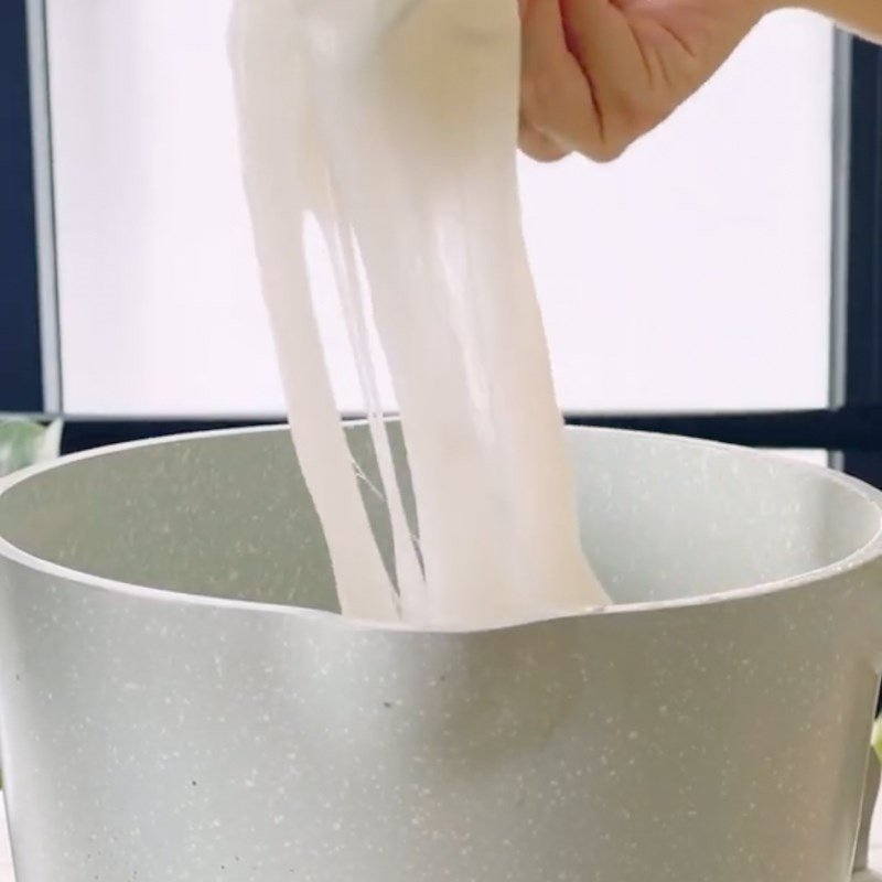 Nồi bột bánh đúc từ cơm nguội đang được nấu và khuấy đều trên bếp lửa nhỏ