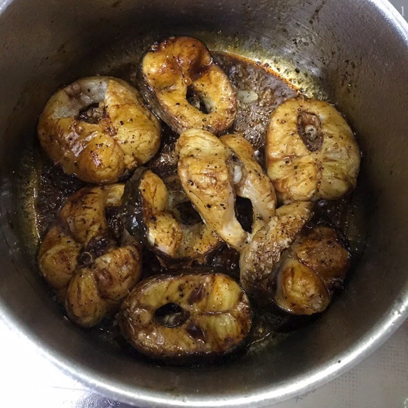 Nồi cá lóc kho tiêu đang sôi liu riu trên bếp, nước kho ngập mặt cá