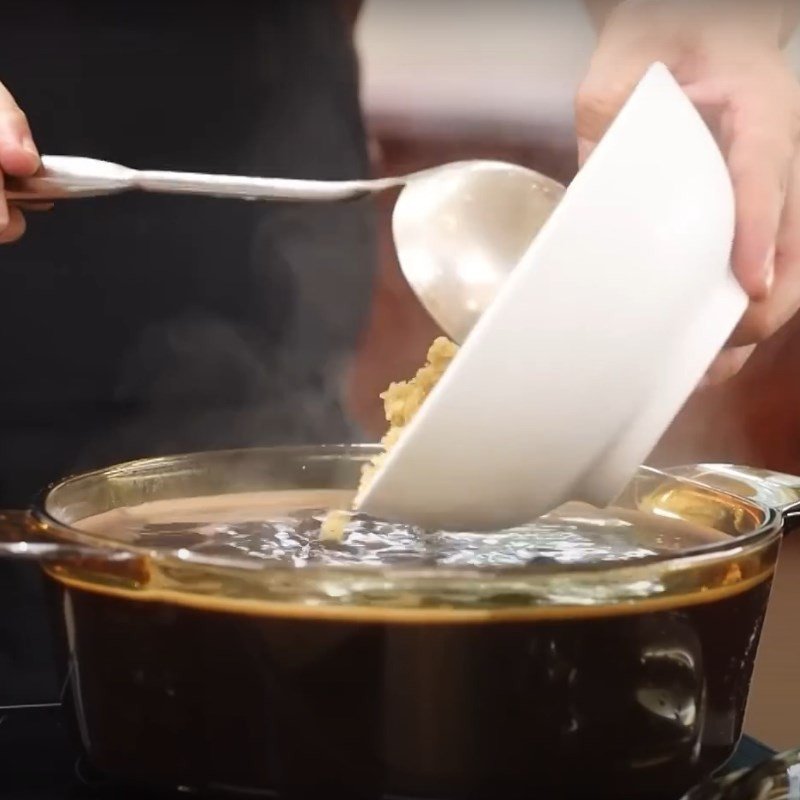 Nồi chè đỗ đen sôi lục bục trên bếp, đang được khuấy đều để tạo độ sánh mịn.