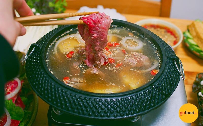 Nồi lẩu bò nhúng giấm chua thanh, hấp dẫn với các loại rau và bún tươi