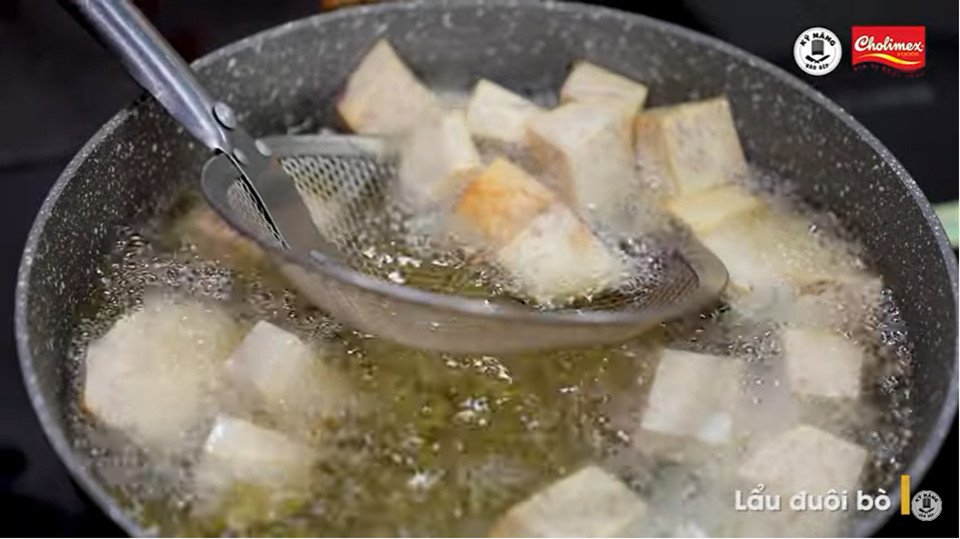 Nồi lẩu đuôi bò đang được hoàn thiện với các nguyên liệu đã chiên sơ