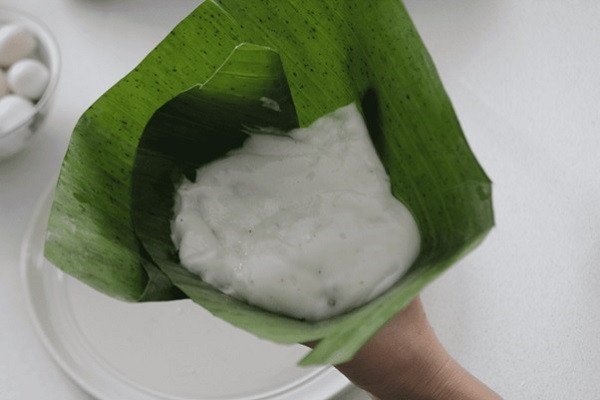 Phủ bột lên trên nhân để hoàn thành gói bánh giò truyền thống