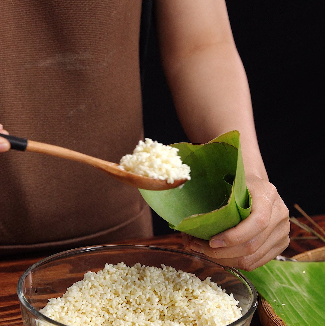 Quá trình gói bánh tro miền Bắc bằng lá tre hoặc lá dong.