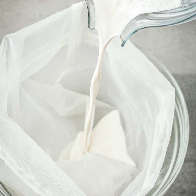 Quá trình lọc sữa hạt lanh qua túi vải để loại bỏ bã, đảm bảo sữa mịn màng và thơm ngon